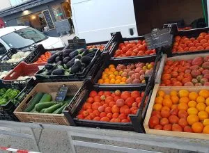 Cageots de tomates rouges et orange, aubergines, courgettes et poivrons sur l'étal du marché.